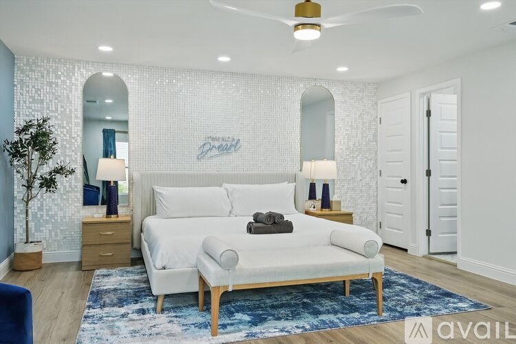 A bedroom with a white bed and a blue rug.