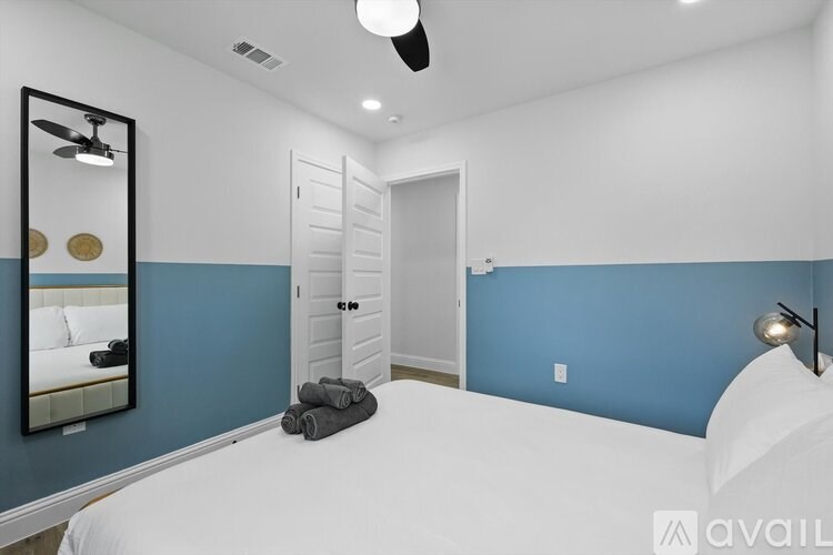 A bedroom with a white bed and a mirror on the wall.