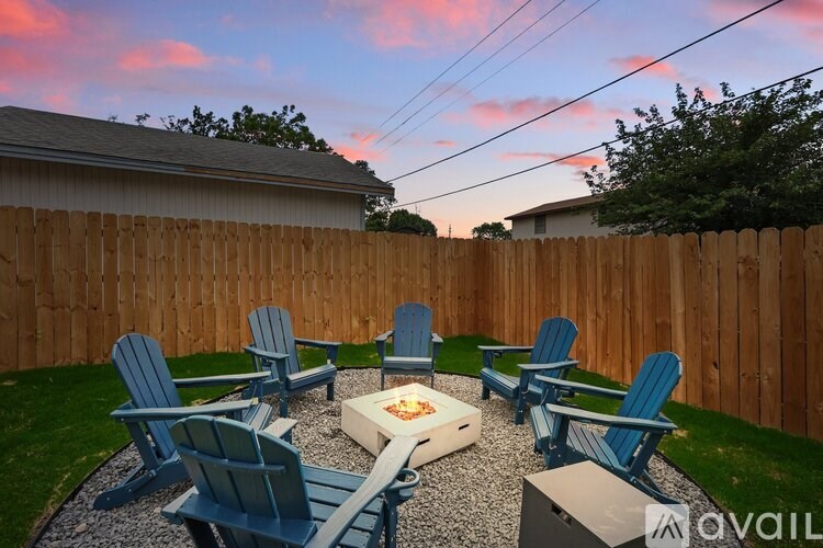 A backyard with a fire pit and chairs.