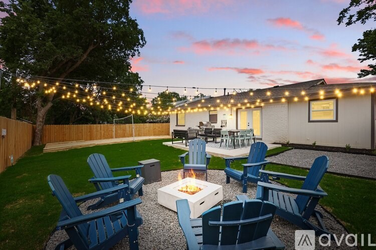 A backyard with blue chairs and a fire pit.