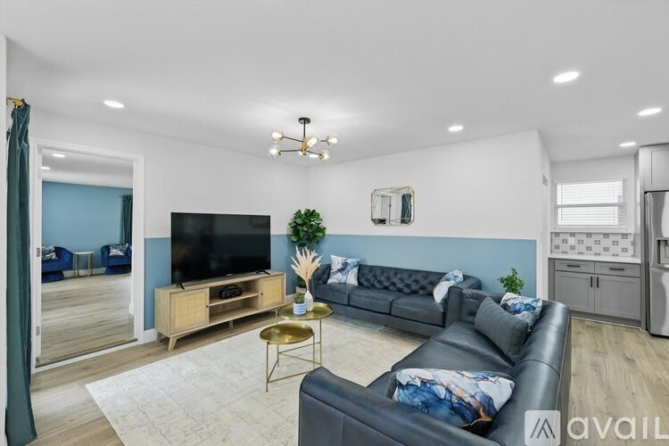A living room with a black leather couch and a wooden entertainment center.