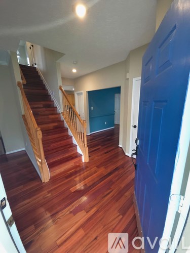 A hallway with a blue door and wooden stairs.