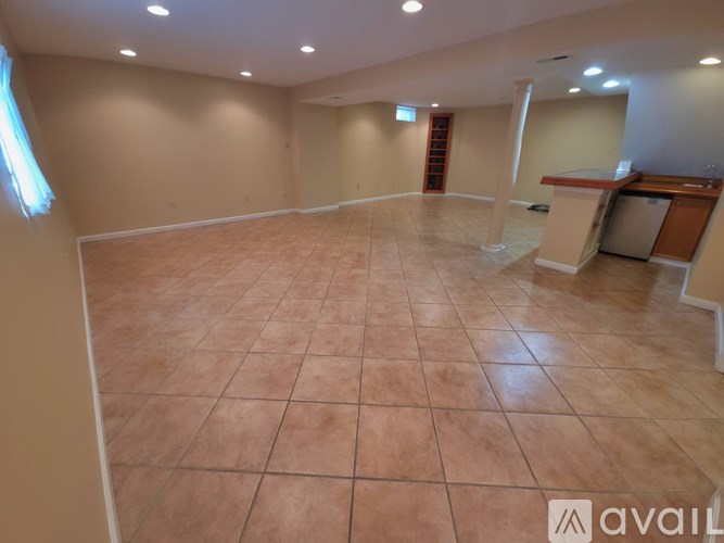 A spacious room with tiled flooring and a bar area.