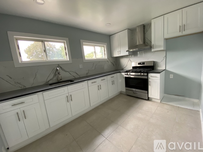 A kitchen with white cabinets and a marble countertop.