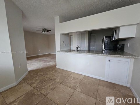 A kitchen area with a counter and a fan on the ceiling.
