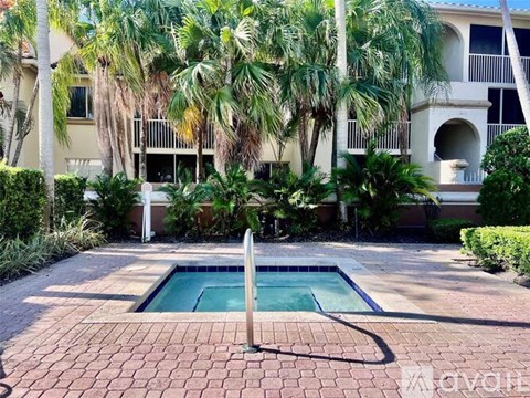 A small pool surrounded by a brick patio and palm trees.