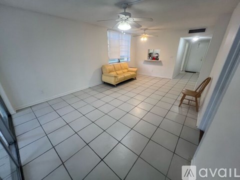 A living room with a yellow sofa and a fan.