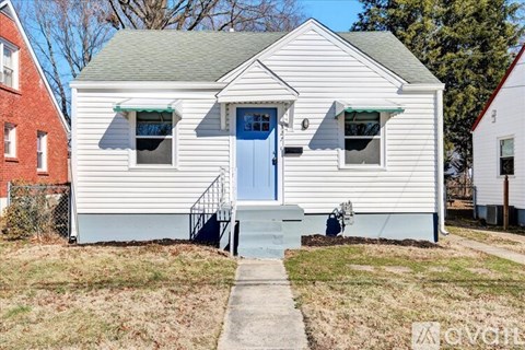 A small white house with a blue door and a small porch.