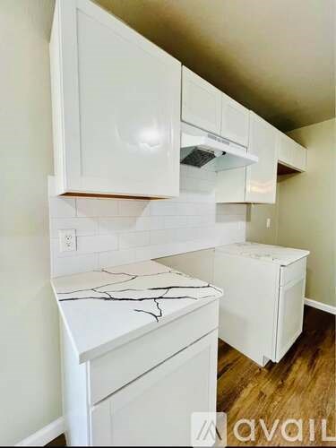 A kitchen with white cabinets and a marble countertop.