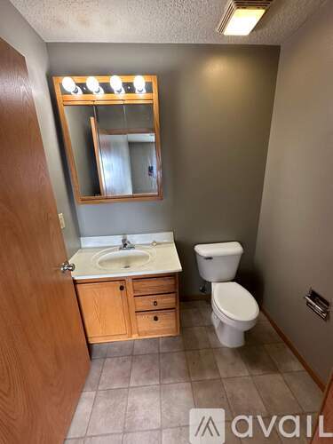 A bathroom with a toilet, sink, and mirror.