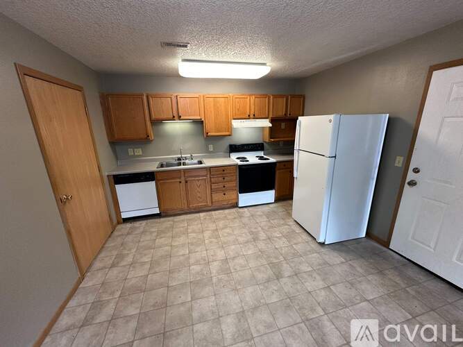 A kitchen with white appliances and wooden cabinets.