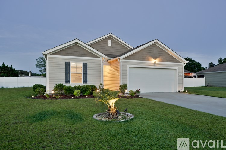 A house with a brown roof and a white fence in the front yard.