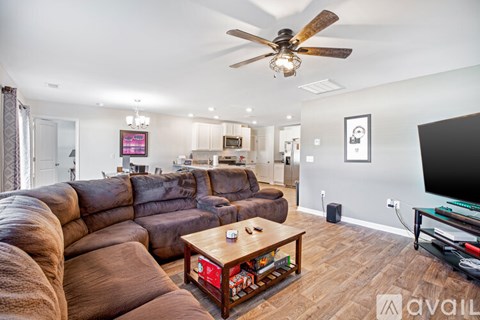 A living room with a brown leather couch and a ceiling fan.