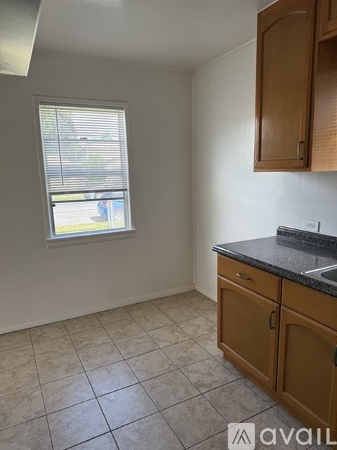 A kitchen with wooden cabinets and a window with blinds.