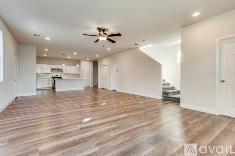 A spacious living room with wooden flooring and a ceiling fan.
