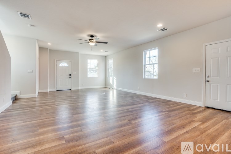 A spacious room with wooden floors and a ceiling fan.