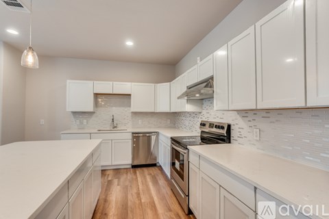 A kitchen with white cabinets and a wooden floor.