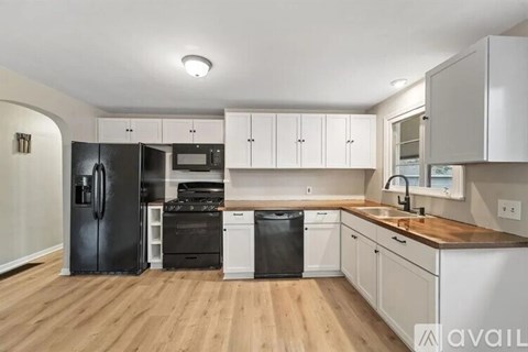 A kitchen with black appliances and white cabinets.