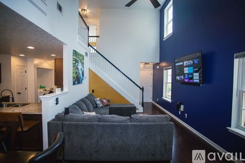 A living room with a grey couch and a television on the wall.