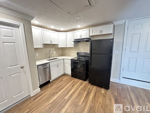 A kitchen with a black refrigerator and wooden floors.