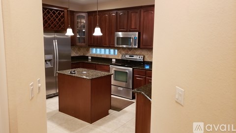 A kitchen with brown cabinets and a granite island.