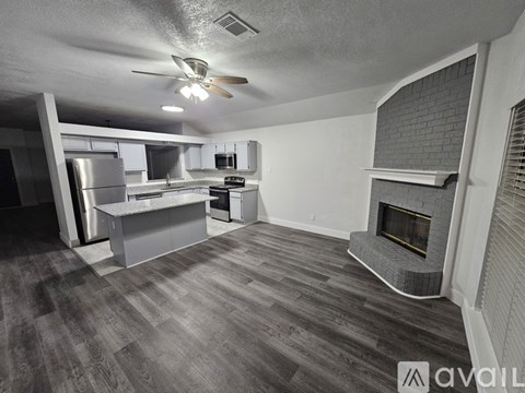 A spacious kitchen and living room with a fireplace and wood flooring.