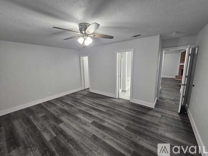 A room with a ceiling fan and wood flooring.