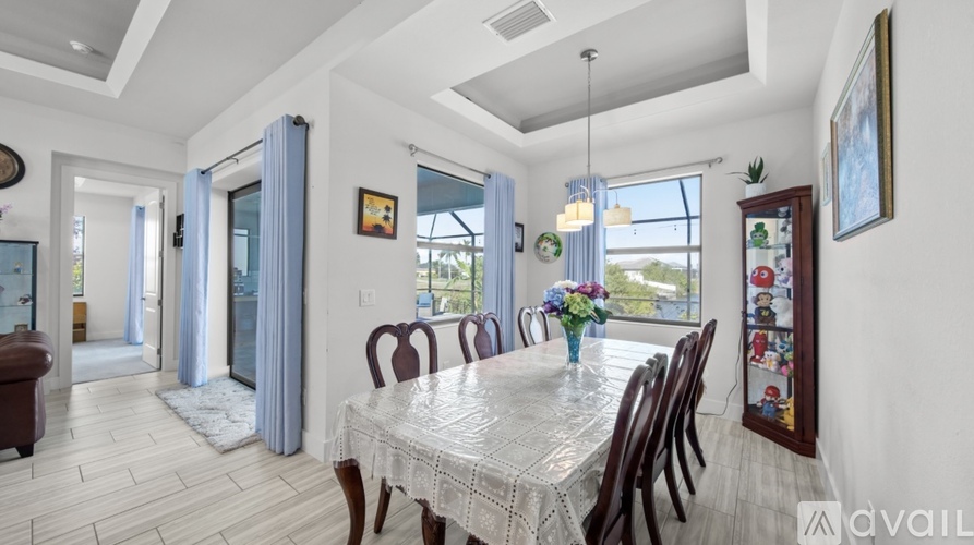 A dining room with a table set for six with a view of the backyard.