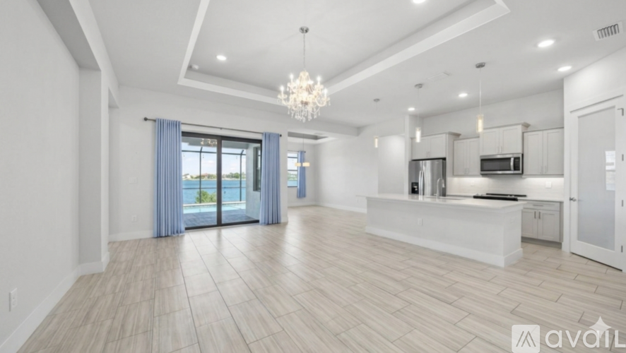 A spacious living room with a kitchen area in the background.