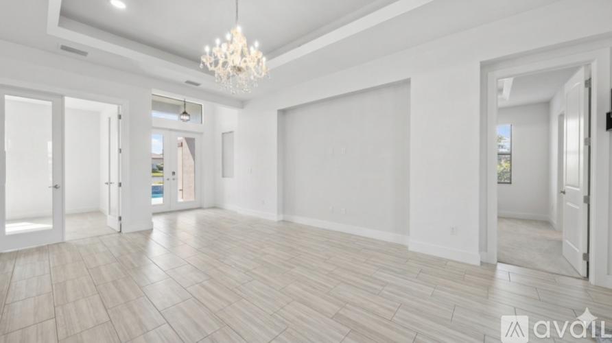 A spacious room with a chandelier and wooden flooring.