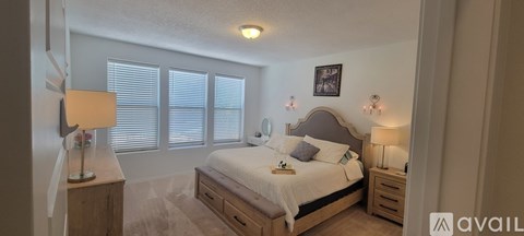 A bedroom with a bed, nightstand, and window with blinds.