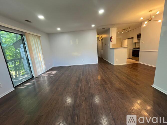 A spacious room with wooden flooring and a large window.