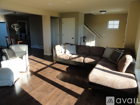 A living room with a brown couch and a white chair.