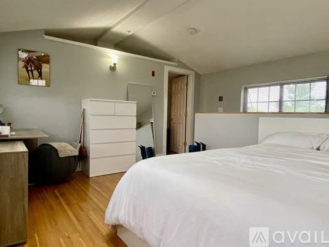 A bedroom with a large bed and a wooden floor.