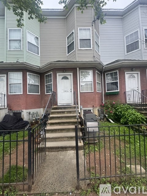 A grey house with a black iron fence in front.