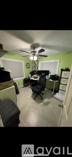 A room with a ceiling fan and a desk with a computer.