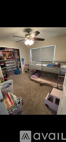 A room with a bed, a ceiling fan, and a window with blinds.