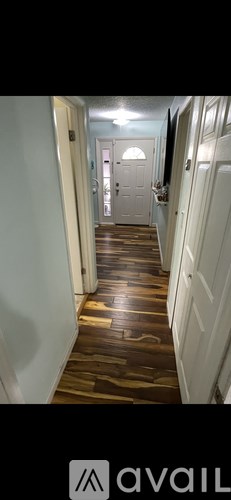 A hallway with wooden floors and white walls.