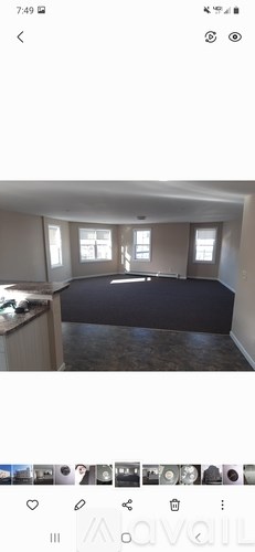 A room with a large window and a dark carpet.