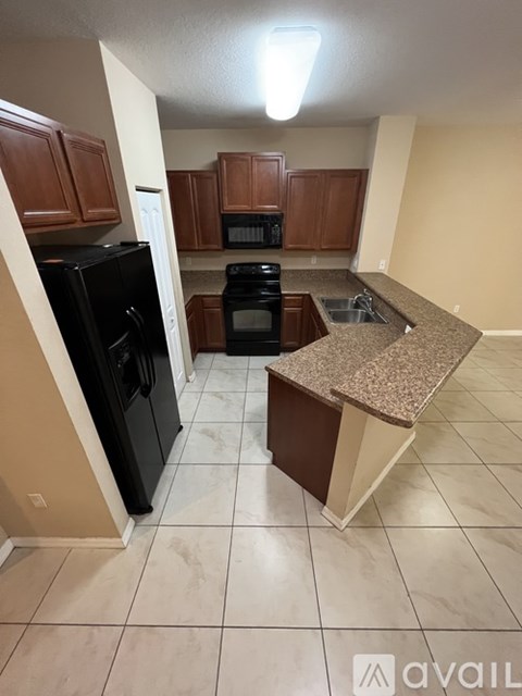 A kitchen with black appliances and brown cabinets.