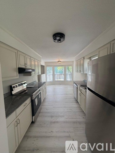 A kitchen with white cabinets and a stainless steel refrigerator.