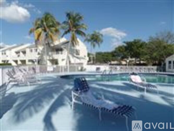 A pool surrounded by lounge chairs and palm trees.