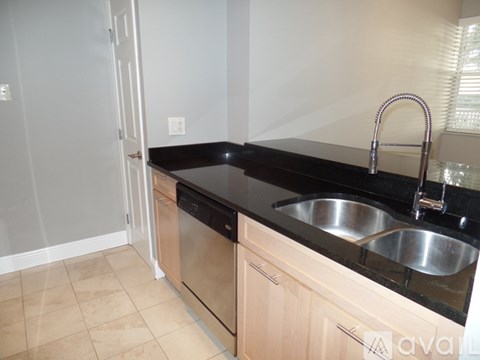 A kitchen with a black countertop and a stainless steel sink.