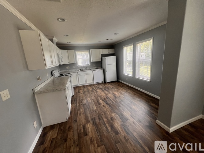 A kitchen with white appliances and wooden floors.
