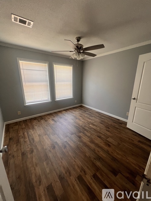 A room with a ceiling fan and wooden flooring.