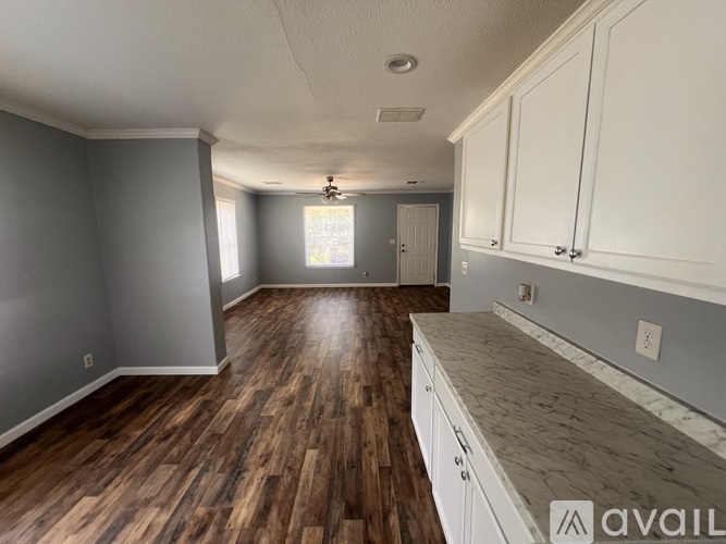 A kitchen with wooden floors and white cabinets.