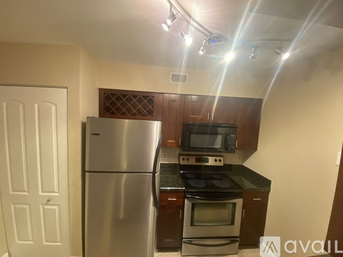 A kitchen with a stainless steel refrigerator, microwave, and oven.