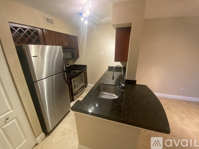 A kitchen with a black countertop and stainless steel appliances.