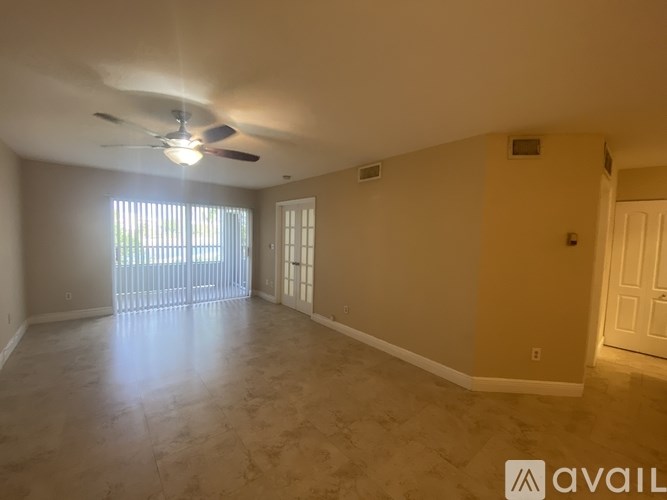 A spacious room with a ceiling fan and sliding glass doors.