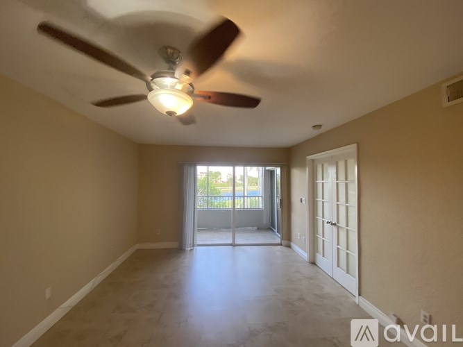 A room with a ceiling fan and sliding glass doors leading to a balcony.